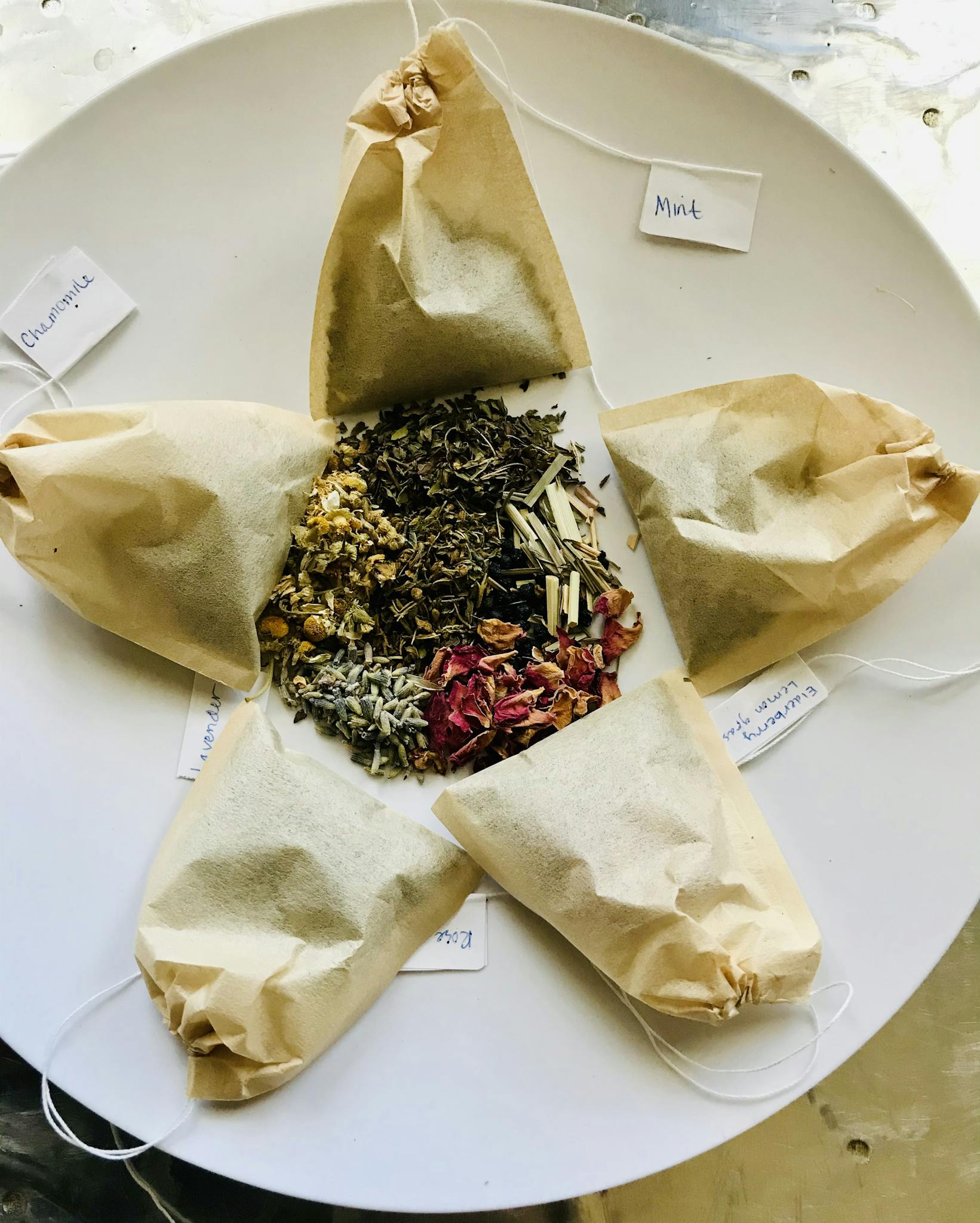 Assorted herbal teabags and loose leaves displayed on a plate for a natural and organic feel.